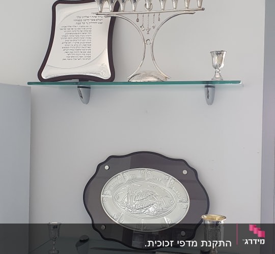 מדפי זכוכית עם חנוכייה וגביעים